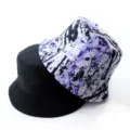 Close-up detail of a reversible bucket hat showing solid black and purple ink splash. - Adult 55-58cm / Graffiti Purple
