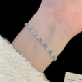 Gros plan d'un délicat bracelet en argent avec des zircons bleus et blancs sur un poignet. - Style de ligne en losange (R5573) / Bleu et Blanc