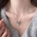 Dettaglio di collana in argento con zircone quadrato e moneta su un maglione grigio - Collana con Pietra a Cubo Argentata (R5602)