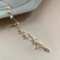 Detalle de cerca de una elegante pulsera de cadena plateada con delicadas perlas colgantes - Estilo Blanco (R2783) / Blanco