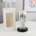 Exquisite preserved blue rose in glass dome detail view with romantic fairy lights and gift bag. - Rose Choice Blue