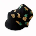 Detailed view of the stylish double-sided bucket hat featuring a trendy pineapple print. - Black Pineapple
