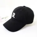 Close-up detail of a black cotton baseball cap with an embroidered white letter R - Adult 55-58cm / Black