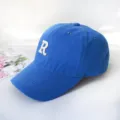 Close-up of blue cotton baseball cap featuring white embroidered R letter on front. - Adult 55-58cm / Blue