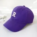 Detailed side view of a purple cotton baseball cap featuring a white embroidered letter R - Adult 55-58cm / Purple