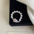 Primo piano di un anello elastico con perle rosa e un ciondolo a forma di zucca di cristallo. - R0876 Anello Elastico Zucca Rosa / Rosa