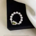 Primo piano di un anello elastico con perle rosa e un ciondolo a cuore in zircone verde - R0994 Anello Elastico Zucca Verde Oliva / Verde Oliva