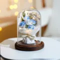 Blaue und weiße konservierte Rosen im Glasdom mit LED-Lichterkette und Holzsockel - 5 roses crushed ice blue (white paper)