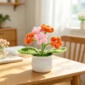 Close-up detail of handmade crochet yarn flowers in a white ceramic pot on a sunny table - 5-Head Baby's Breath Potted Plant / Pink+Orange