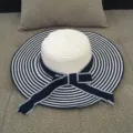 Stylish women's wide brim straw sun hat featuring navy blue and white stripes with ribbon bow. - M (56-58cm) / Striped Navy