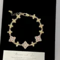 Primo piano di un bracciale dorato con fiori a quattro petali in cristallo rosa. - Bracciale Fiore a Quattro Foglie (R2512) / Rosa