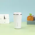 Detailaufnahme eines weißen isolierten Edelstahl-Kaffeebechers auf einem bunten Schreibtisch - 380ml / Weiß