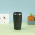 Dunkelgrüner vakuumisolierter Edelstahl-Kaffeebecher auf einem dekorativen Schreibtisch - 380ml / Grün