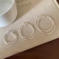 Tre paia di orecchini a cerchio d'argento minimalisti in varie dimensioni su lino - 2.5cm / Argento