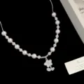 Elegante collana di perle con ciondolo a fiore bianco e perline lucide su sfondo nero - Collana con Fiori di Conchiglia e Sfera di Strass (R1910)