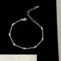 Gros plan détaillé d'un élégant bracelet argenté style bambou avec oxydes de zirconium. - Style Bambou (R5820) / Blanc