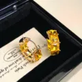 Vista macro dettagliata di orecchini a cerchio in oro con strass gialli quadrati - Strass Dorato (R5340)
