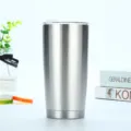 Primer plano del vaso de acero inoxidable con acabado metálico cepillado y tapa transparente. - 20oz / Natural
