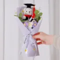 Hand hält einen Abschlussbär-Blumenstrauß mit handgefertigten Häkelblumen - Lila