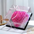 Gros plan d'un coffret cadeau de roses en forme de cœur holographique avec couvercle transparent. - Modèle haut de gamme enceinte Bluetooth et lumière / Cœur Miroir - Rose Colorée - Rouge Rose