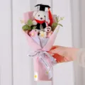 Detailansicht eines weißen Abschluss-Teddybären mit roter Quaste und handgestrickten Blumen - Rosa