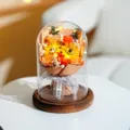Nahaufnahme eines Sonnenblumenstraußes in einer Glaskuppel mit warmen LED-Lichtern - Large Glass Dome And Charcoal Wood Base / 2 Sonnenblumen + Champagner Rose