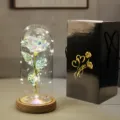 Primo piano di una rosa galassia in cupola di vetro accanto a una confezione regalo - Black Gift Box Wood Base / Oro Arcobaleno