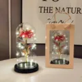 Detail view of the glowing gold foil rose inside a clear glass dome with gift box setup. - Black Base Gold Foil Red Flower Glass Cover