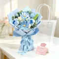Hand-crocheted blue flower bouquet with light blue wrapping and transparent gift bag. - Blue Galsang Flower & Rose Bouquet / Trapezoid Bag