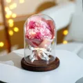 Konservierter rosa Rosenstrauß in Glaskuppel mit LED-Licht auf dunklem Holzsockel - 3 carnations pink