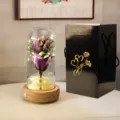 Détail de rose éternelle violette sous cloche en verre avec LED et boîte cadeau noire - Boîte Noire en Carton Ondulé (Base Bois + 2 Fleurs de Savon + Boîte Musique) / Violet