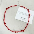 Handmade red string necklace with red agate beads on a minimalist white background card - Necklace