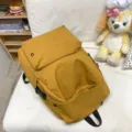 Minimalistischer gelber Rucksack mit großer Kapazität für Studenten auf einem Sofa. - 1 / Orange