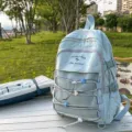 Stylish light blue large capacity backpack for students shown in an outdoor park setting - Blue