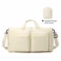 Detailed view of the foldable beige travel duffel bag, showing front pockets and compact storage shape. - Pale Yellow