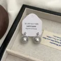 Primo piano di eleganti orecchini a perno con perla grigia e zircone in un portagioie - Stile Perla Grigia Zircone (R1403)