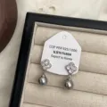 Detailansicht eleganter französischer Kristallklee- und grauer Perlenohrringe auf Schmucktablett. - Vierblättriges Kleeblatt Graue Perle Stil (R0373)