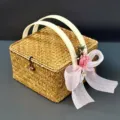 Détail de boîte-cadeau en paille tressée à la main avec poignées blanches et nœud rose. - L 20 x l 20 x H 11 cm / Panier en tulle rose