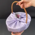 Elegant handheld wedding gift basket wrapped in lavender satin with floral accent - Basket + Wrap + Flowers / Purple