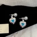 Detail of silver heart earrings featuring blue zircon gems and elegant white pearl studs - Blue Heart Stud Earrings (R1539)