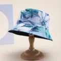 Close-up of a floral print bucket hat for sun protection on a wooden display stand - Blue-green