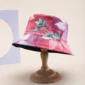 Detailed macro view of a pink floral print bucket hat displayed on a classic wooden stand - Pink Purple Green