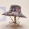 Close-up of tropical leaf print wide brim bucket hat with chin strap for beach sun protection. - Leaf Pink