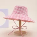 Detailed view of the pink plaid bucket hat, featuring a wide brim and cute bow tie strap. - Grid Pink