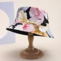 Detailed macro view of high-quality casual floral bucket hat on a wooden display stand - 粉黄黑大朵印花
