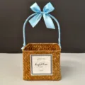 Close-up of a handmade square woven straw gift basket with an elegant light blue ribbon - Orange Basket (Glacier Blue Ribbon)