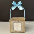Close-up of a square woven gift basket with a light blue silk ribbon bow - White-Washed Basket [Glacier Blue]