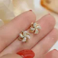 Dettaglio di orecchini a perno a forma di mulino a vento dorati e rotanti lucidi. - Stile Mulino d'Oro / Oro
