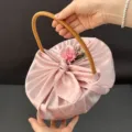 Detailed view of elegant pink silk-wrapped gift basket with rattan handle for weddings - Basket + Wrap + Flowers / Pink