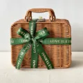 Detailed macro shot of a hand-woven wicker gift basket with an elegant green ribbon. - Medium Size 26x17x11cm / Dark Green Ribbon + Suitcase Box